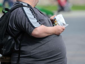 An overweight man eating junk food