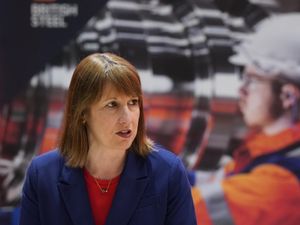 Rachel Reeves in front of a picture of steelworkers