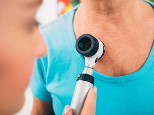 A doctor examining patient skin moles with dermoscope