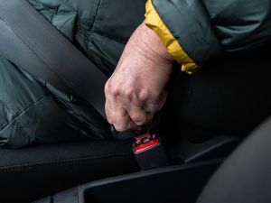 An older woman fastens her seat belt