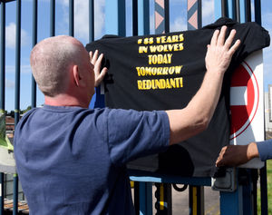 Another t-shirt is held up at the gates to the Bushbury Lane site