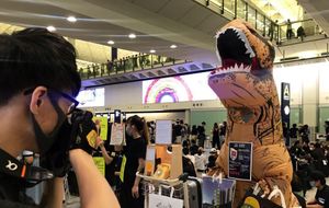A masked man and a protestor dressed as a dinosaur at Hong Kong airport. Picture: Krissi Carter