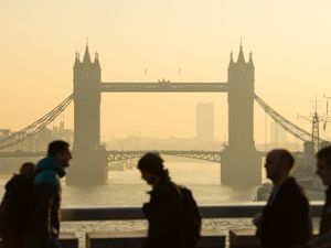 Commuters walk in London with a bridge in the background