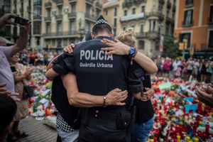 A police officer hugs people near the tributes