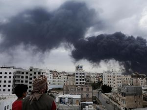 Yemenis watch as smoke billows following Israeli airstrikes targeting a power plant and Sanaa Airport