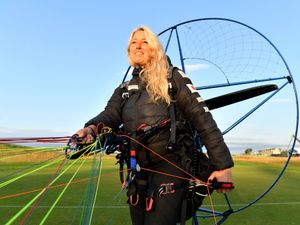 Sacha Dench smiling while attached on the ground to a paramotor