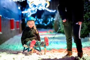 Young girl being pulled on a sled through snow at Santa’s Winter Wonderland at the SnowDome.