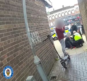 The officer is on the ground surrounded by colleagues and members of the public who stopped to help after he was hit by the e-scooter, also pictured