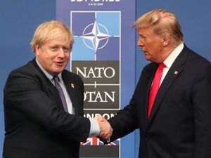 Boris Johnson shakes hands with Donald Trump in front of a Nato sign