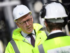 John Swinney in hard hat and hi-vis talking to a worker