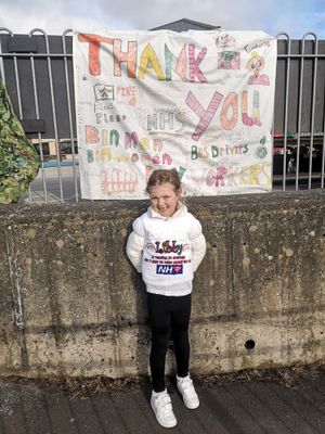 Libby New, aged 5, outside the banner made by key worker's children at Weston Rhyn Primary School
