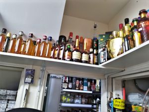 Some of the alcohol on shelving at Super Mahan during the seizures in June 2023 and of the seized alcohol in storage.