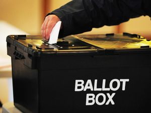 Man puts folded ballot paper into ballot box