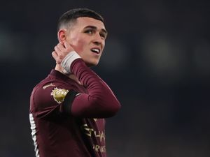 Manchester City forward Phil Foden puts his right hand up to his neck