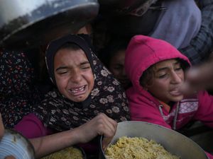 Palestinian girls struggle to reach for food at a distribution centre in Khan Younis, Gaza Strip