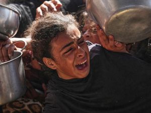 A girl cries as she struggles to get food