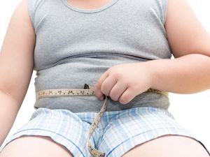 An obese boy measuring his belly with measurement tape