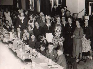 It's over – adults wearing party hats laid on a spread as children enjoy an after war party in Newport