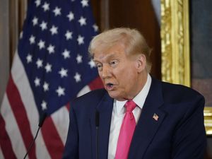 Donald Trump speaking in front of the US flag
