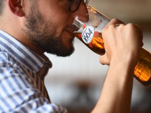 A man drinks a Kronenbourg beer in a pub in Fulham,