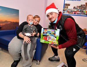 Walsall FC players visit Walsall Manor Hospital. Jamie Jellis hands over a present to Jay Jackson and son Grayson, aged 3.