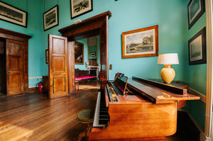 The ballroom is an impressive sight – a brightly coloured room with chandeliers, a statement fireplace, bar area, and even a piano.