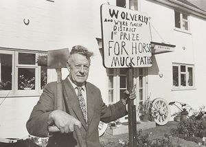 Stourbridge Road, Wolverley - Walter Lawrence was calling on Wyre Forest Council to pass a bye-law forbidding horses from fouling on pavements, after having consistent problems outside his house. The photograph shows Walter outside his house holding a sign that reads 'Wolverley and Wyre Forest District 1st Prize for Horse Muck Paths.'