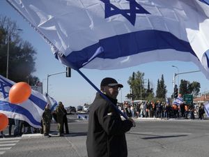 Israelis gather on the side of a road where the funeral convoy carrying the coffins of slain hostages Shiri Bibas and her two children, Ariel and Kfir, will pass by near Kibbutz Yad Mordechai, Israel