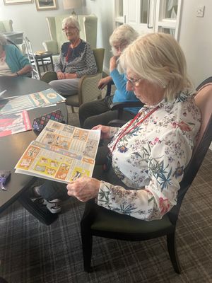 Resident looking at vintage magazine at HC-One’s Priorslee House Care Home from the Boots memory boxes