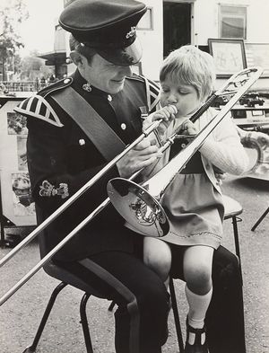'Huffing and puffing without much success is five-year-old Miranda Harthill of Springhill Road, Rugeley. Showing her the trombone is Sergeant Major Pete Smith, of Leek, a member of the Staffordshire Regiment band. The band is on a summer tour of Staffordshire and Miranda met them when they visited their town.' - July 1980.