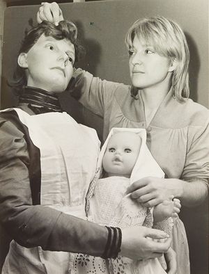 A Victorian Nursery exhibition at Walsall Art Gallery in 1983. The exhibition included a reconstructed nursery from the period, along with various Victorian dolls and games. The photograph shows Lindsey Brooks preparing models of a nanny and baby.