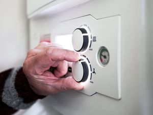 A pensioner adjusting his boiler controls