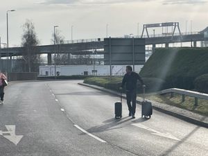 Man with suitcases walking at the roundabout outside Heathrow Airport