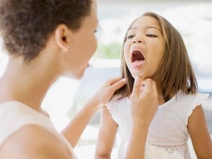 A mother checks her daughter's tongue