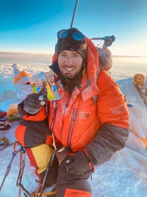 Adam climbing Everest, holding photos of his wife Helen, with their son, William. Just three days after he returned from Everest, Helen gave birth to their daughter, Emily.