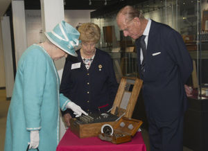 Queen Elizabeth II presses the button to start the Enigma code breaking machine watched by the Duke of Edinburgh and wartime operator Ruth Bourne during a visit to Bletchley Park, Milton Keynes.