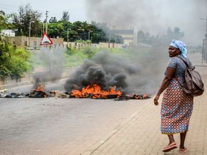 A woman walks past a barricade set on fire by protesters in Maputo, Mozambique