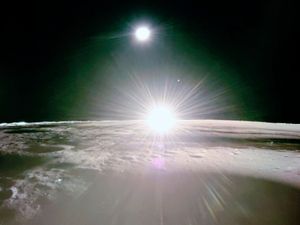 The sun setting on the moon, with Earth and Venus in the distance.