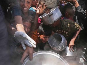 Palestinian children struggle to get donated food at a community kitchen in Beit Lahia