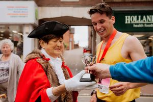 Daniel Connolly was the first man to cross the finish line in the marathon and is handed a trophy by Mayor of Bridgnorth Jean Onions



