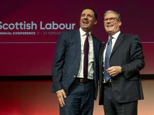 Anas Sarwar and Sir Keir Starmer smiling in front of Scottish Labour signage
