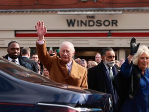 King and Queen waving in front of a business called The Windsor