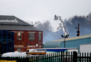 Firefighters on an aerial platform douse the flames at the site