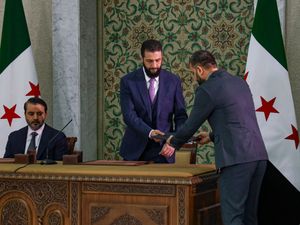 Syria’s interim president Ahmad Al-Sharaa, centre, prepares to sign a temporary constitution for the country in Damascus