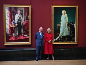 Charles and Camilla standing in between their two full-length portraits