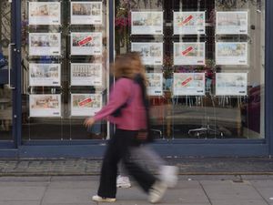 People walk past an estate agent's window