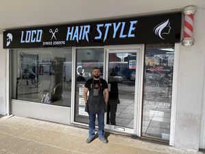 Alan Nadir, owner of Loco Hairstyle, stands in front of his shop