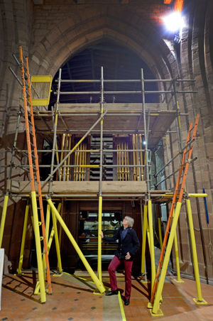 Rev Sally Day next to the scaffolding needed to rebuild the organ