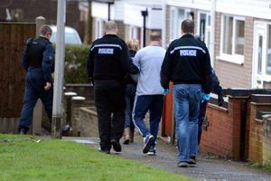 A man is led away during an early morning raid