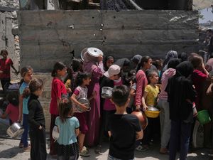 Palestinians line up for donated food at a community kitchen